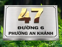 Bảng số nhà inox xước bạc số vàng gương nổi 3D viền vát chéo bốn mặt phong cách cổ điển sang trọng – chụp góc cao nền cây xanh tối nổi bật