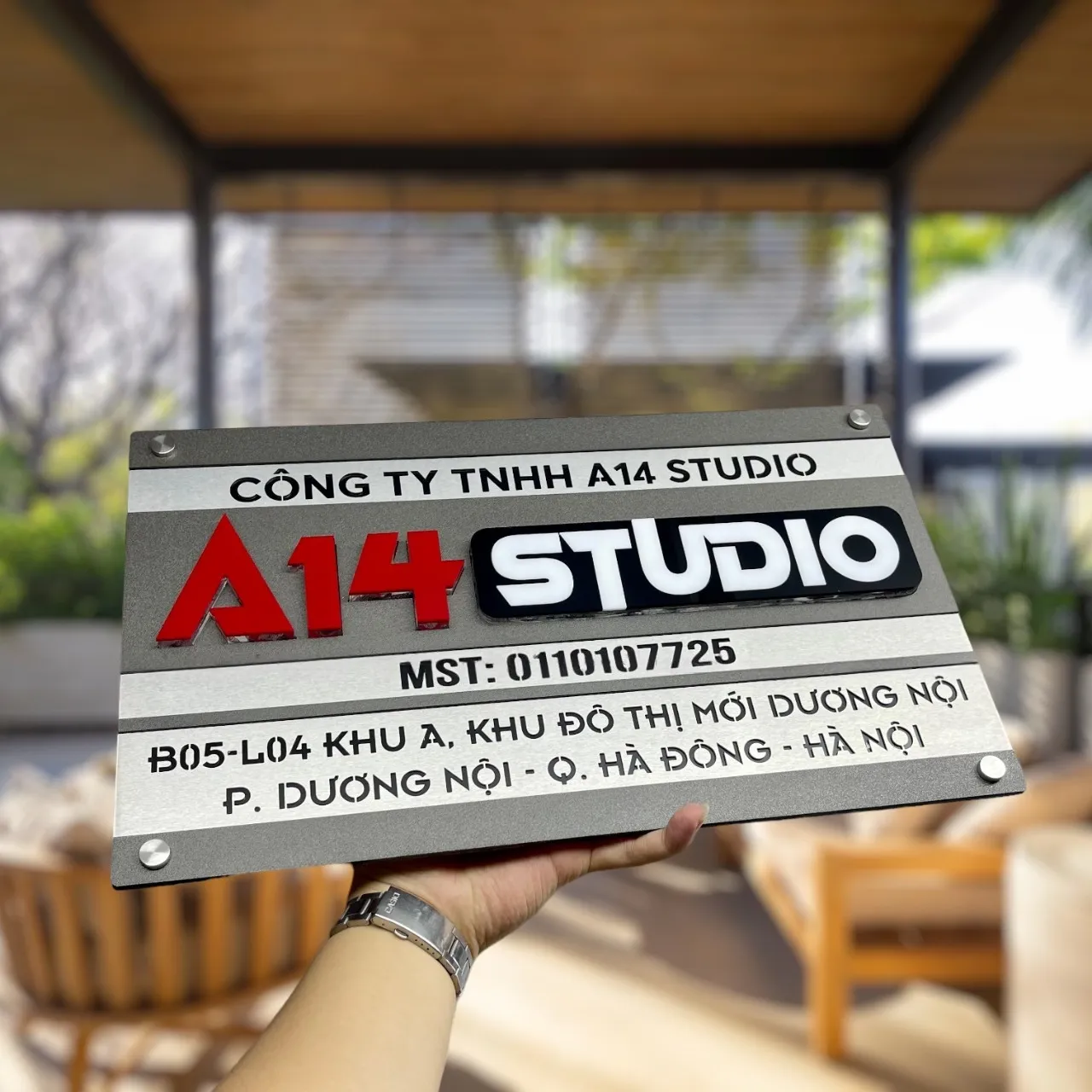 Cận cảnh chữ nổi 3D inox sơn đỏ và khối logo STUDIO đen trắng nhiều lớp trên bảng hiệu công ty inox xám khói