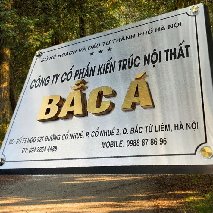 bảng hiệu công ty inox bạc xước chữ nổi vàng gắn mặt tiền ngoài trời nhìn từ xa nhận diện rõ ràng