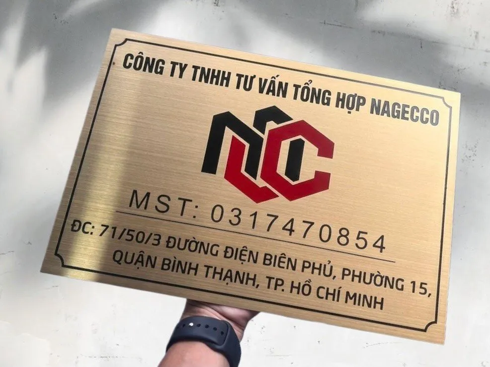 Cận cảnh chữ ăn mòn inox sơn tĩnh điện trên bảng hiệu công ty vàng xước Cận cảnh chữ khắc ăn mòn kim loại sơn tĩnh điện đen đỏ trên nền inox 304 vàng xước
