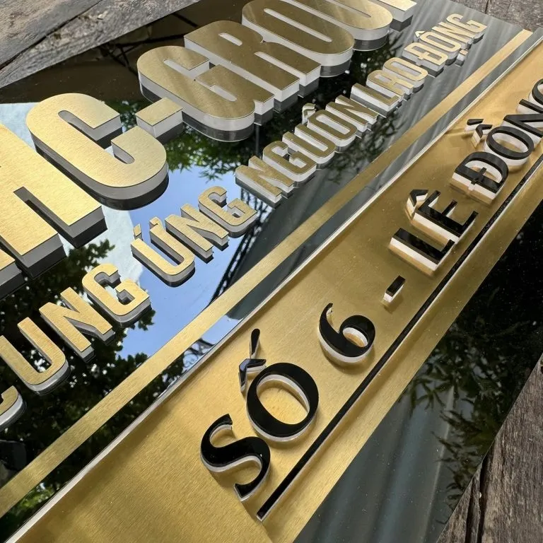 Cận cảnh chữ nổi 3D inox vàng xước dày 15mm trên bảng hiệu công ty inox nền đen