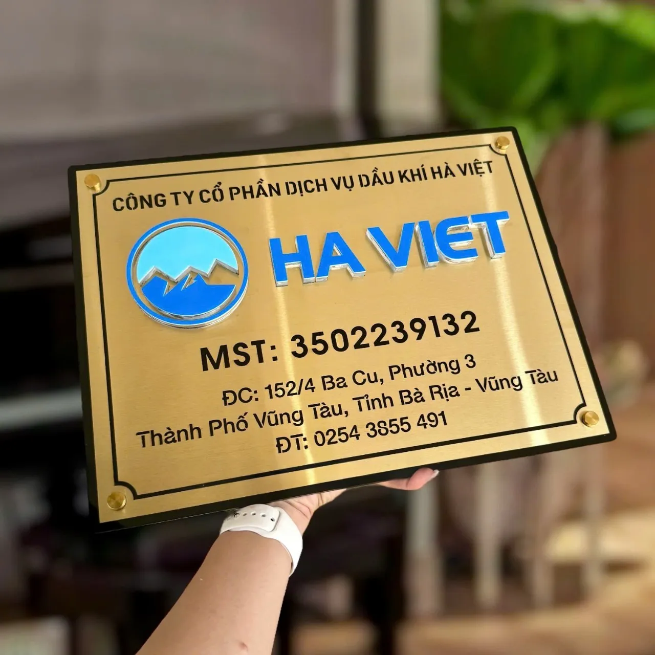 bảng hiệu công ty inox vàng xước đặt trên nền đế đen tạo hiệu ứng layering vàng trên đen sang trọng