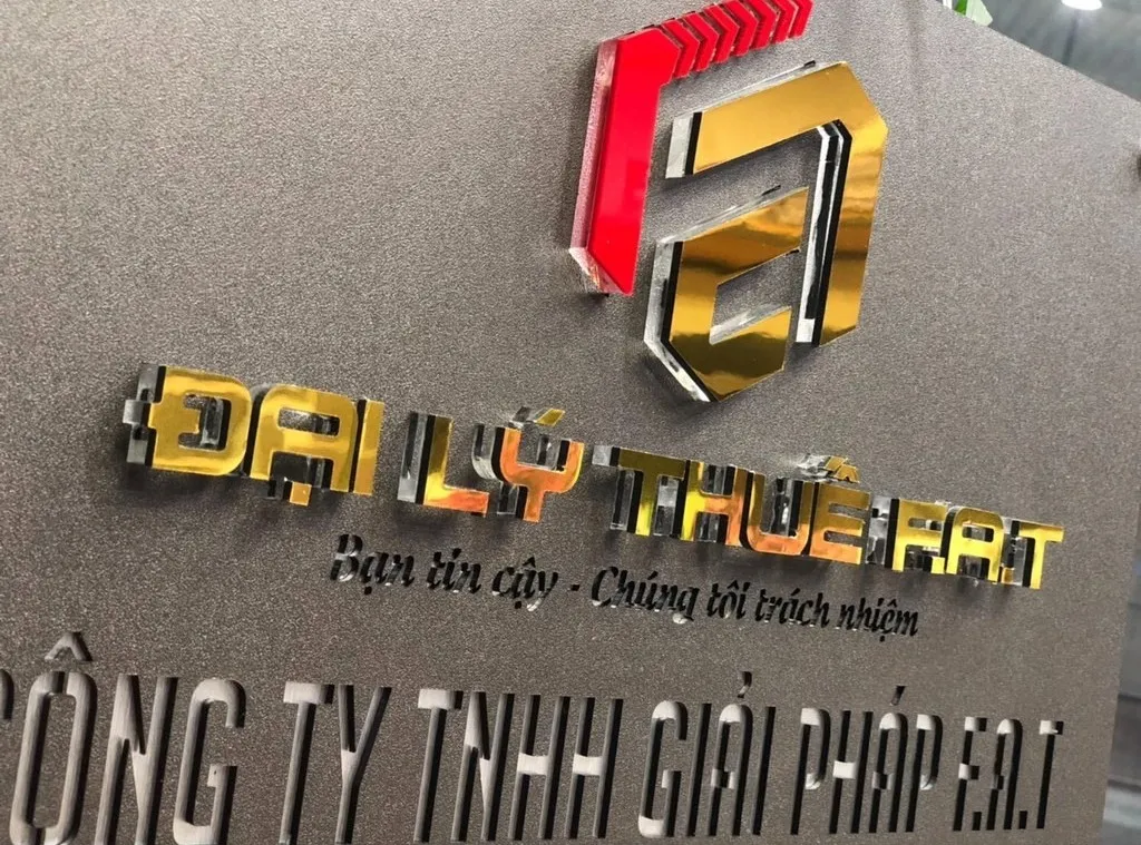 Cận cảnh logo 3D inox đa màu vàng gương đỏ bạc gương nổi trên nền inox xám khói sơn tĩnh điện mịn