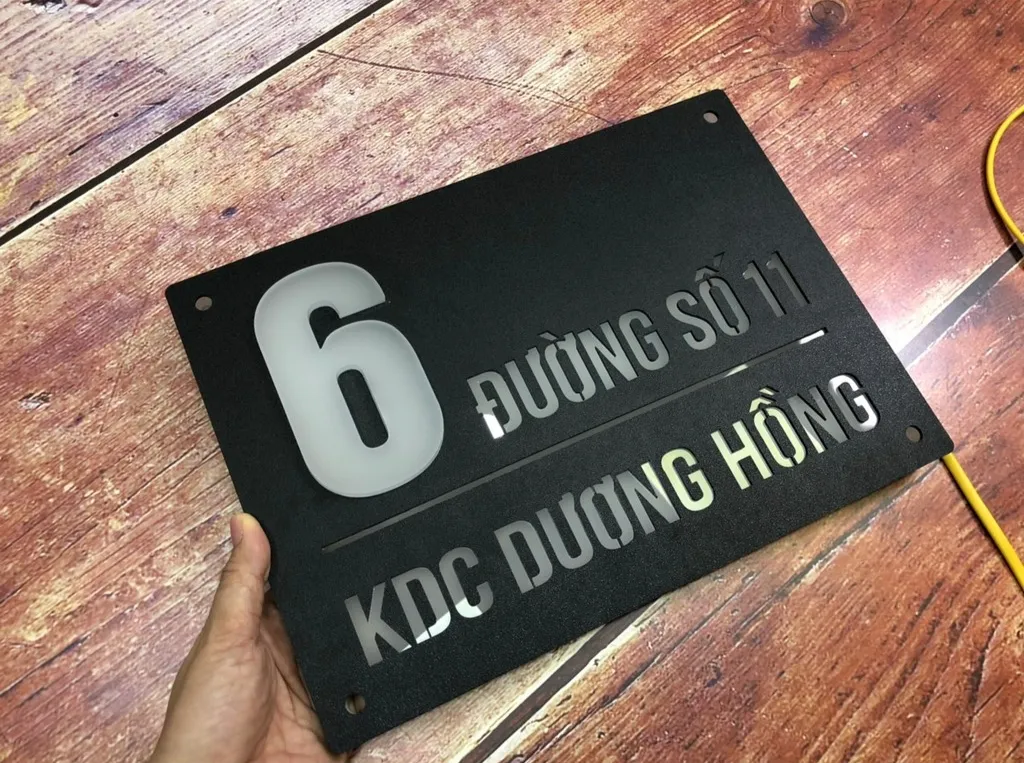 Bảng số nhà 3D mica hút nền đen matte cầm tay mặt trước ban ngày – số mica mờ và chữ CNC rõ nét