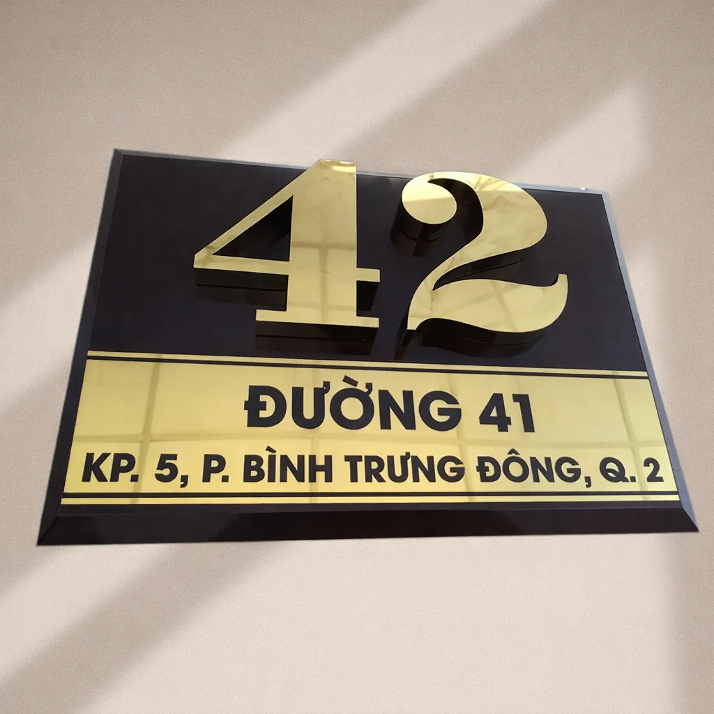 Bảng số nhà nền đen chữ vàng nổi 3D – góc nghiêng ngang thấy rõ dải địa chỉ vàng và cạnh vát chéo