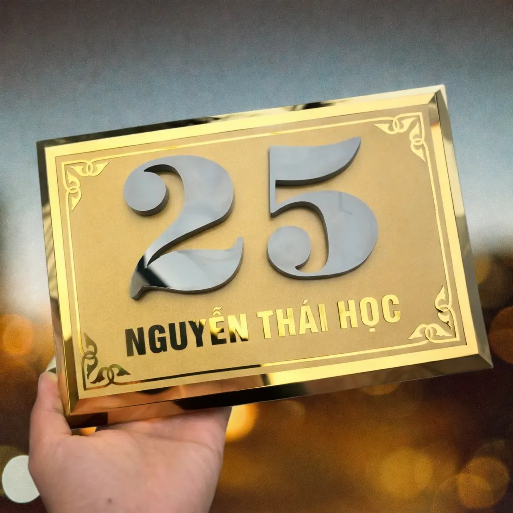 Bảng số nhà inox vàng hoa văn cổ điển – chi tiết cạnh vát chéo bóng loáng Bảng số nhà inox vàng hoa văn cổ điển – cạnh vát chéo 4 mặt bóng gương nhìn từ góc nghiêng