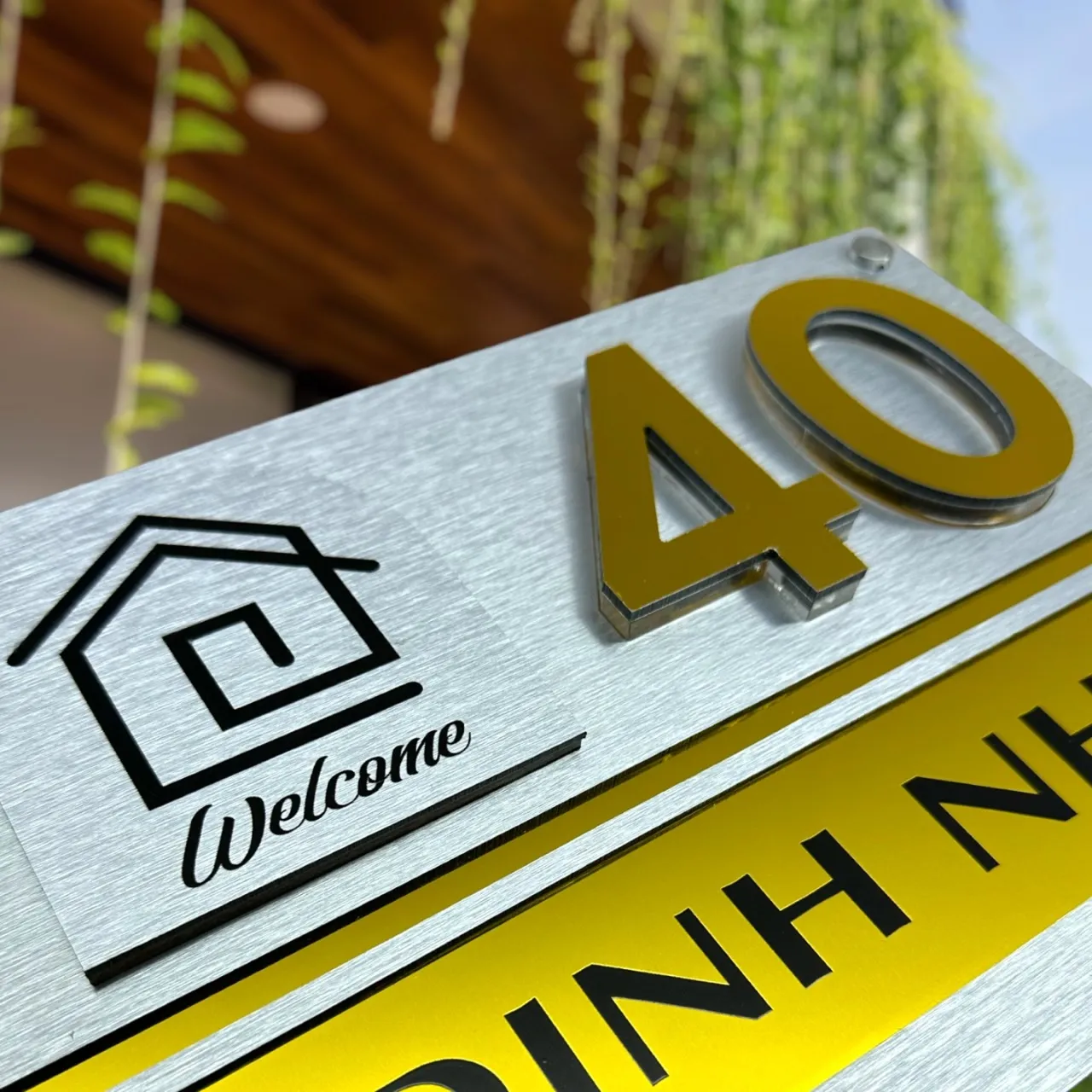 Cận cảnh chữ số nổi 3D inox 304 vàng gương cao 10mm, viền inox bạc trên nền inox xước bạc