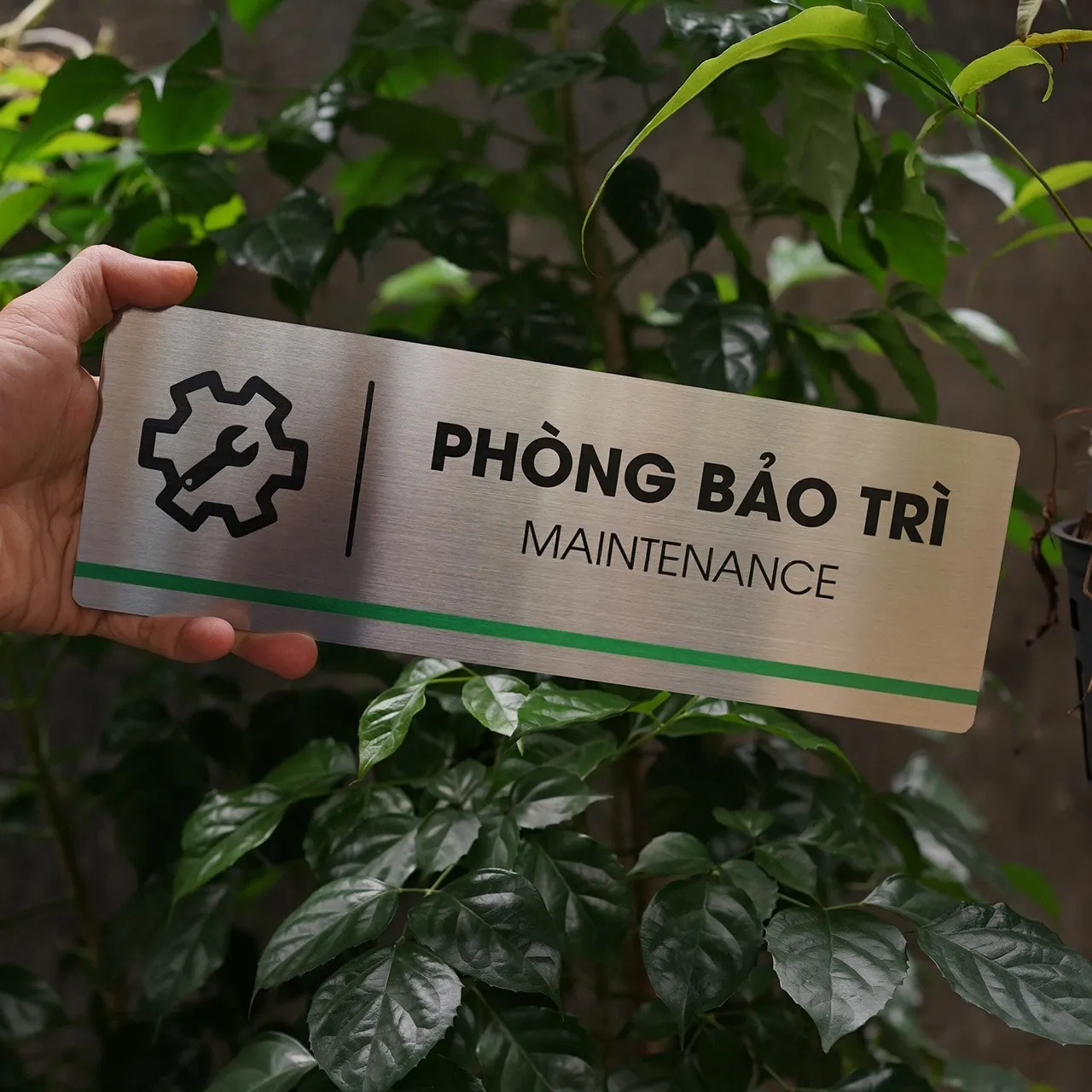 Bảng tên phòng inox 304 cầm trên tay, phối cảnh thực tế ngoài trời