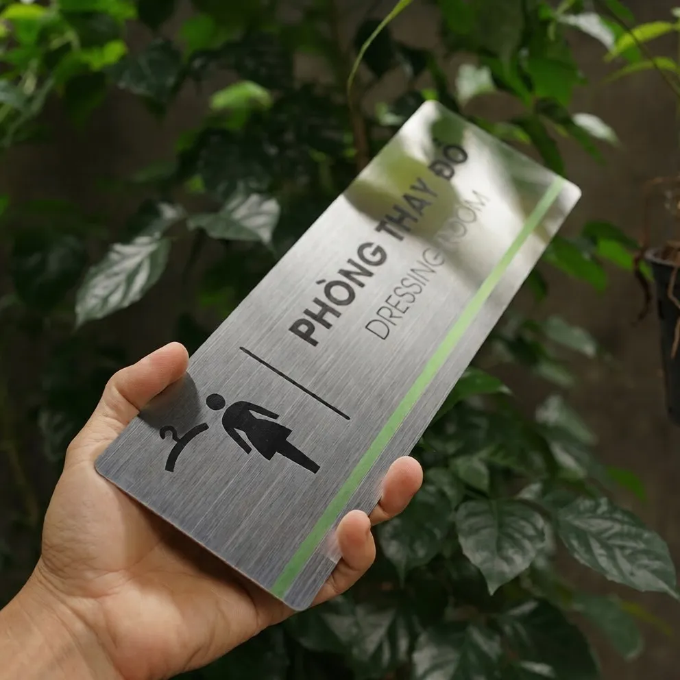 Cận Pictogram Phòng Thay Đồ – Ăn Mòn Hóa Học Sắc Nét Trên Inox 304 Phay Xước Cận cảnh pictogram phòng thay đồ móc áo và nhân vật nữ ăn mòn hóa học sắc nét trên inox 304 phay xước góc nghiêng