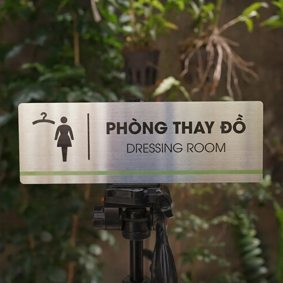 Bảng Tên Phòng Thay Đồ Inox 304 – Mặt Trước Thẳng Thấy Rõ Pictogram Và Sọc Xanh Lá Bảng tên phòng thay đồ inox 304 trên giá đỡ mặt trước thẳng thấy rõ pictogram móc áo nhân vật nữ và sọc xanh