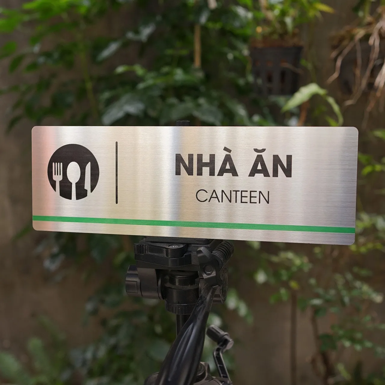 Góc nghiêng 45° bảng tên nhà ăn canteen inox 304 – cận icon ẩm thực và sọc xanh Góc nghiêng 45 độ bảng tên nhà ăn canteen inox 304 brushed, thấy rõ icon đĩa nĩa và sọc xanh lá