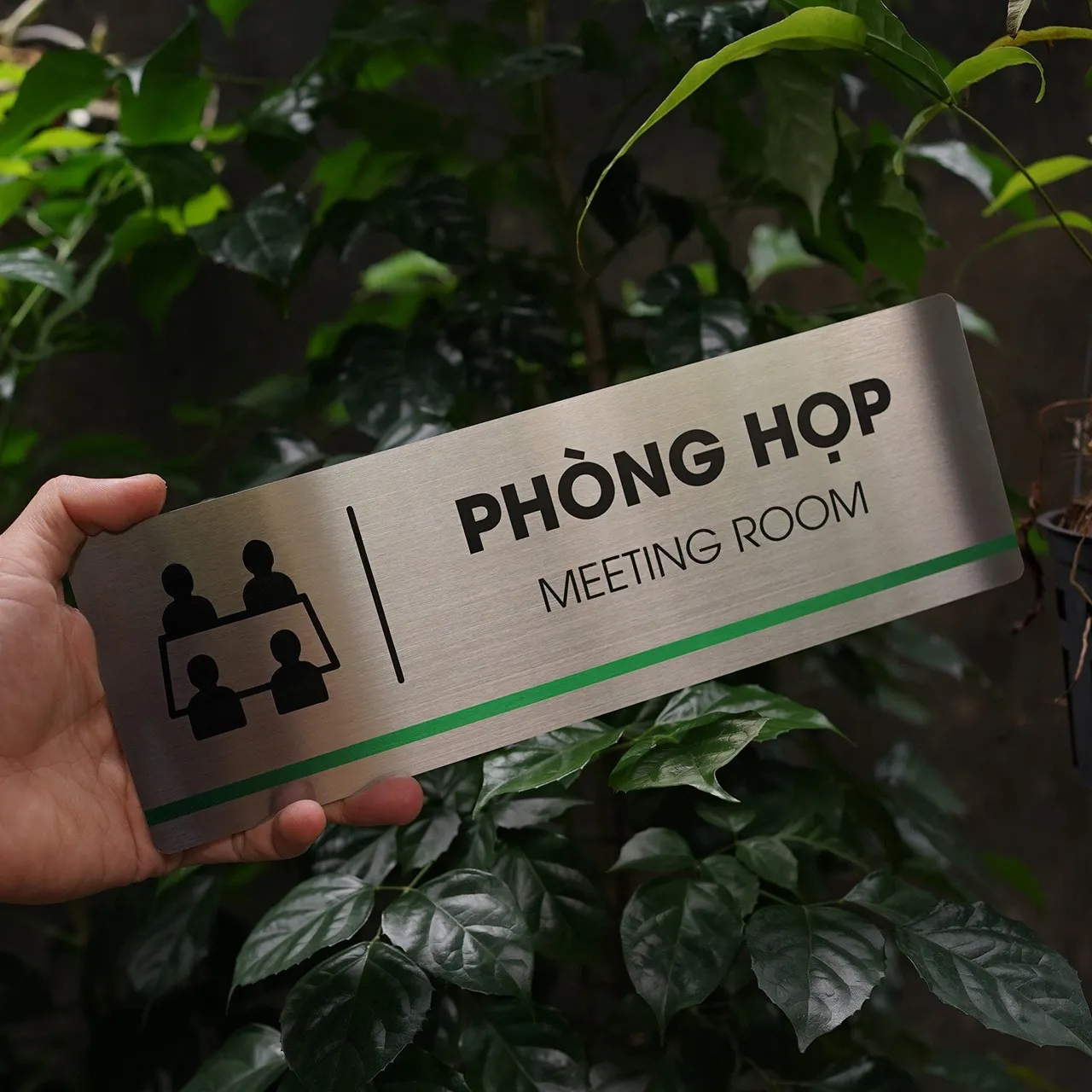 Bảng tên phòng họp inox 304 cầm tay góc nghiêng phải thấy rõ pictogram bốn nhân vật quanh bàn họp