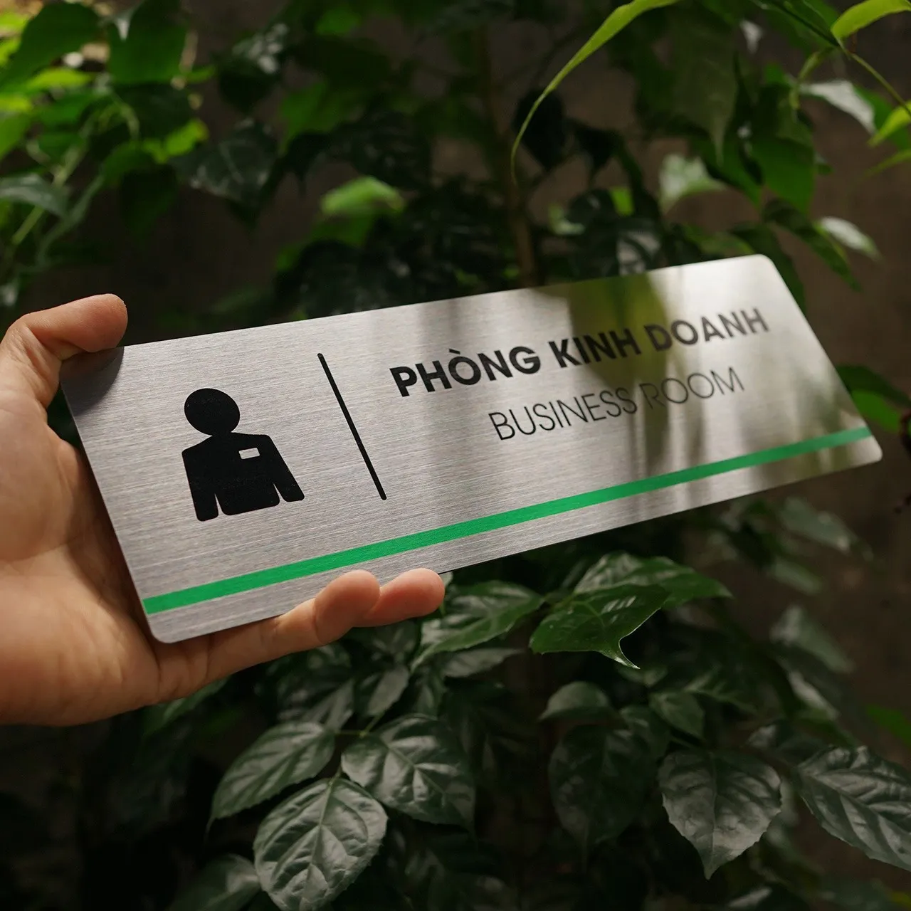 Bảng tên phòng kinh doanh inox 304 cầm tay góc nghiêng phải thấy rõ chữ ăn mòn và pictogram vest thẻ đeo