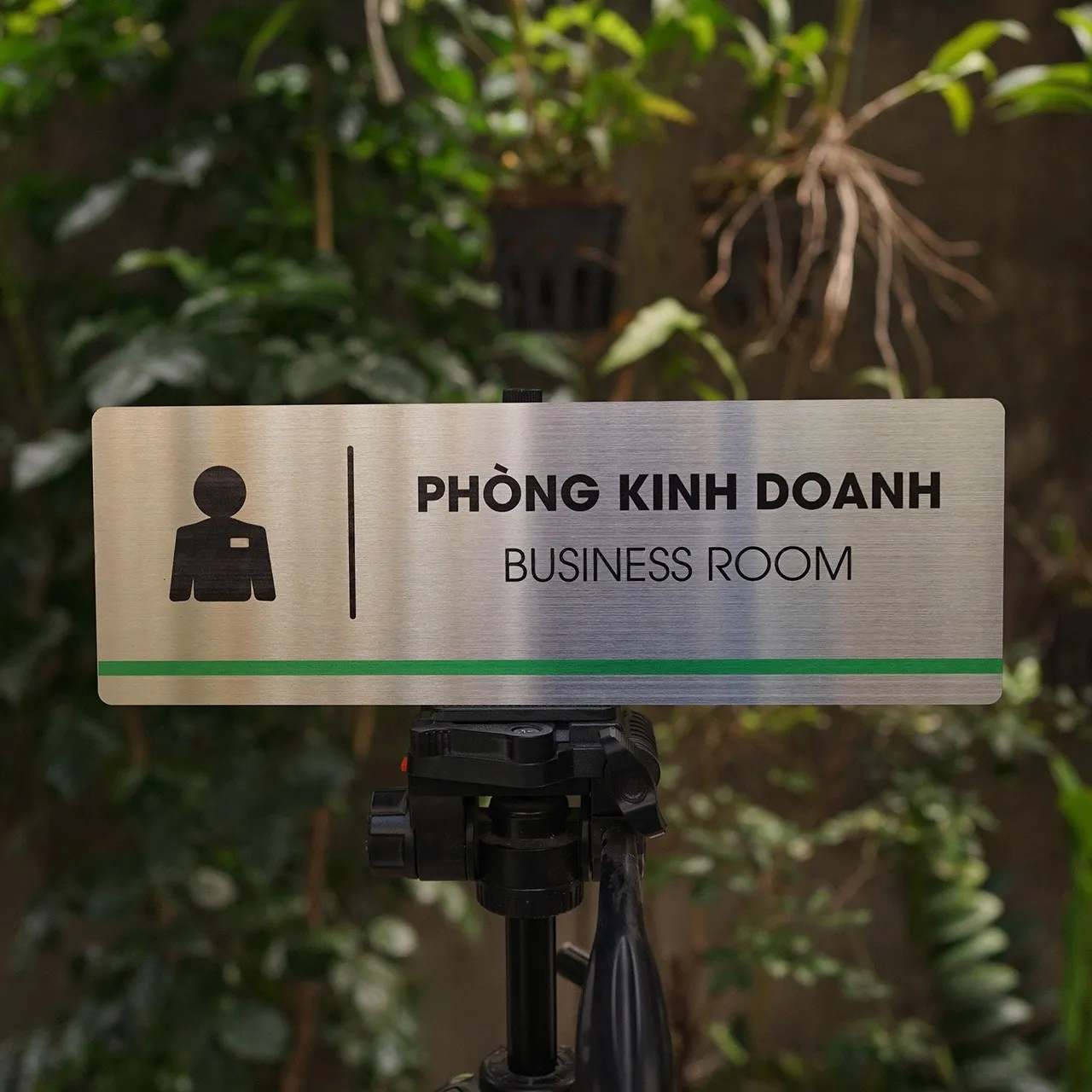 Bảng tên phòng kinh doanh inox 304 trên giá đỡ mặt trước thấy rõ sọc xanh lá và pictogram