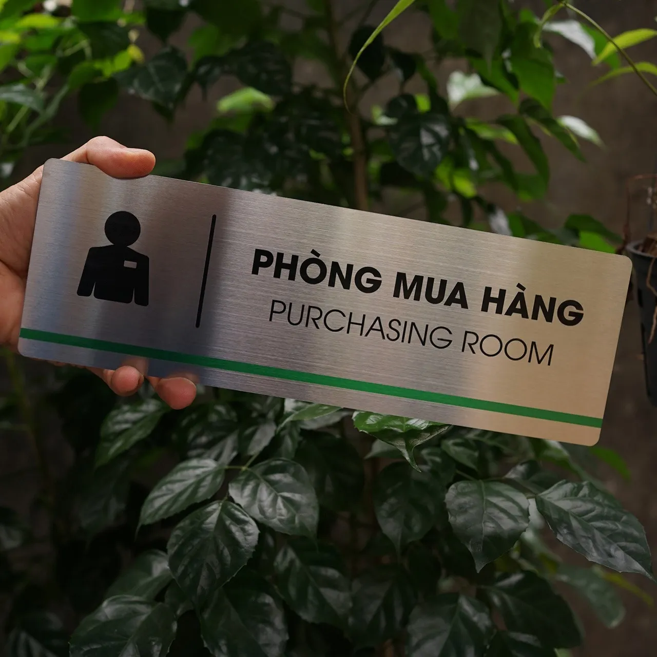 Bảng tên phòng mua hàng inox 304 cầm tay góc nghiêng trái thấy rõ chữ UV và sọc xanh lá
