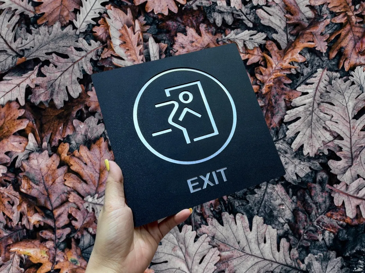 Biển exit inox 304 sơn tĩnh điện đen chụp từ góc thấp, thấy hiệu ứng phản chiếu ánh bạc từ vùng CNC