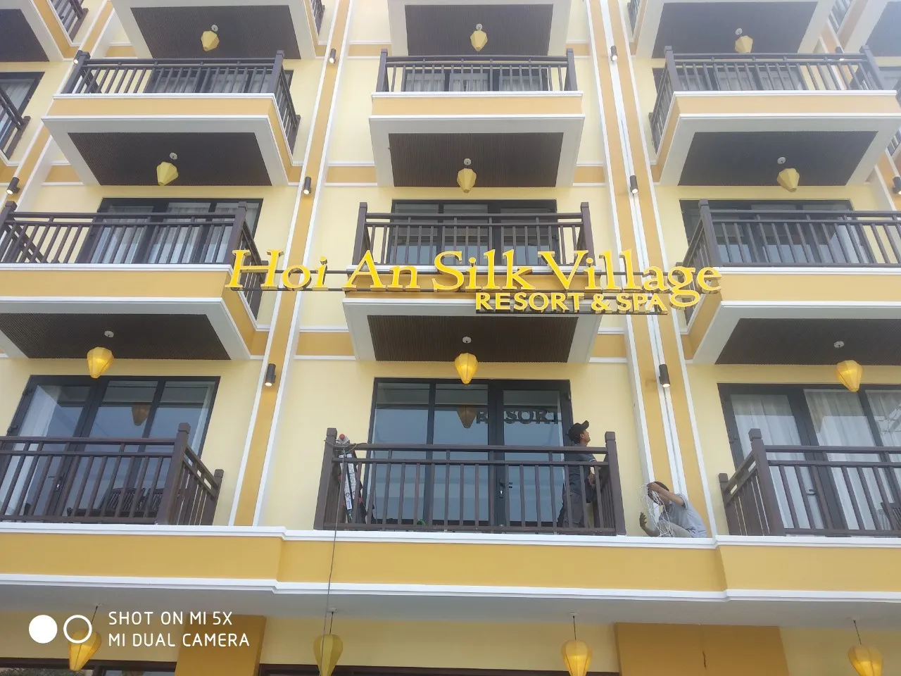 Bảng Hiệu Hoi An Silk Village Resort Ban Ngày Mặt Tiền Bảng hiệu resort Hoi An chữ vàng trên mặt tiền tòa nhà cao tầng ban ngày