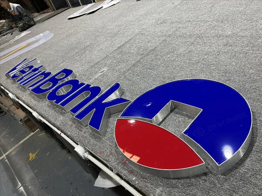 Logo tròn VietinBank cận cảnh mica xanh 70% và đỏ 30% viền inox xước