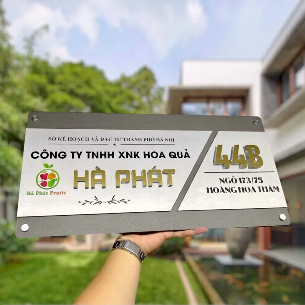 Bảng hiệu công ty inox 2 lớp xám khói chữ nổi 3D vàng xước chụp chính diện thấy rõ logo và địa chỉ
