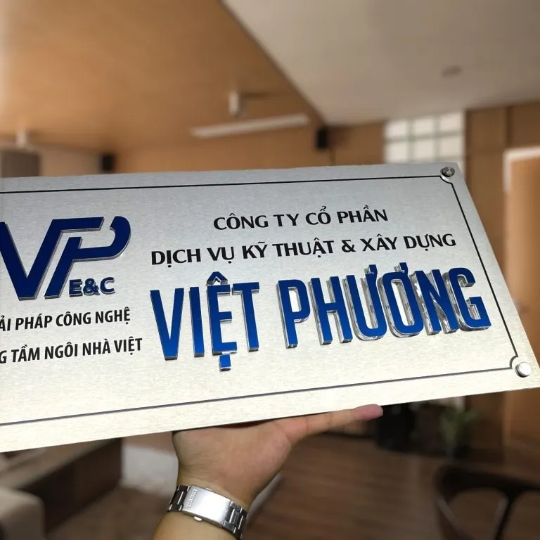 bảng hiệu công ty inox bạc chữ nổi sơn màu bố cục 2 cột viền khung đơn trong không gian văn phòng hiện đại