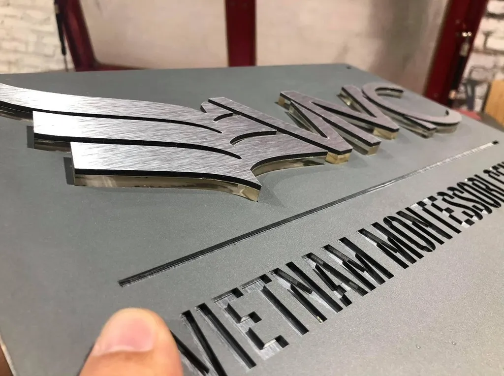 Cận cảnh logo nổi 3D inox bạc xước và viền cạnh sắc nét trên bảng hiệu công ty – Bảng Hiệu Vàng