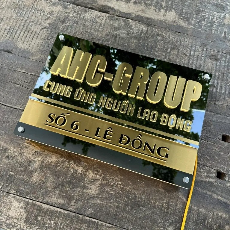 Bảng hiệu công ty inox vàng xước chữ nổi 3D LED halo đặt trên bề mặt gỗ phối cảnh thực tế