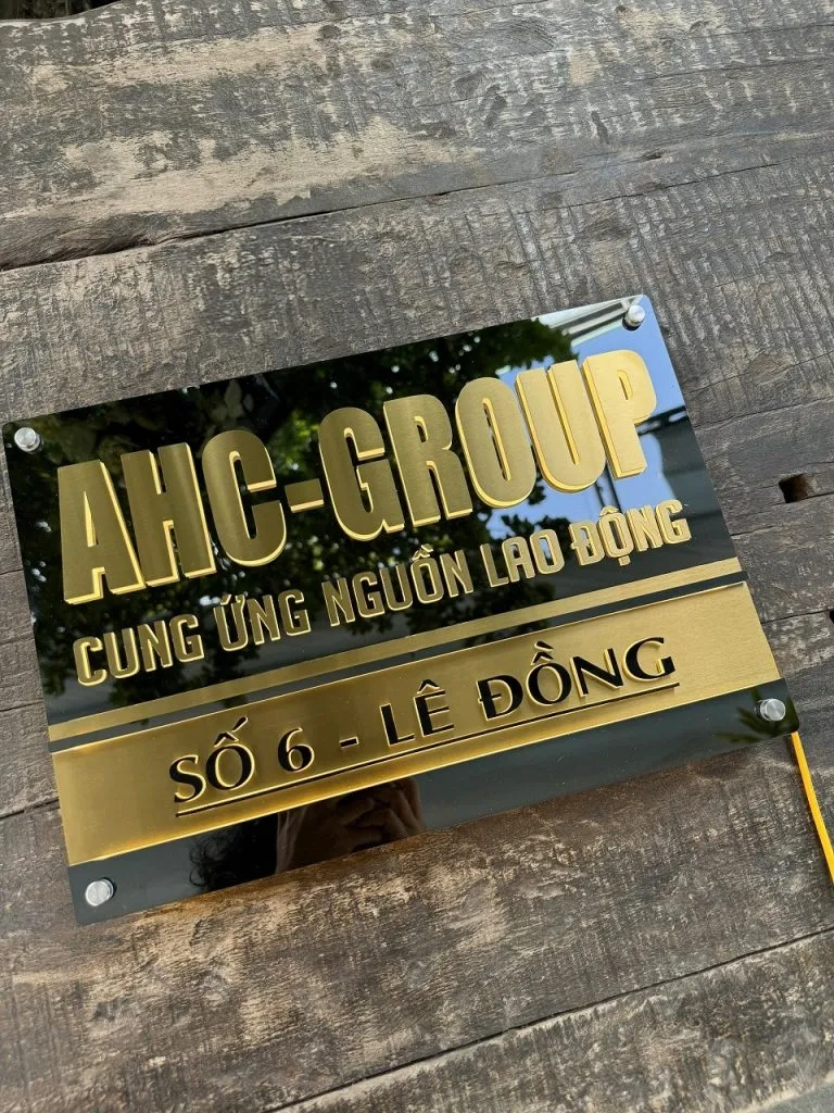 Bảng hiệu công ty AHC Group inox vàng xước nền đen chữ nổi 3D đèn LED halo backlit