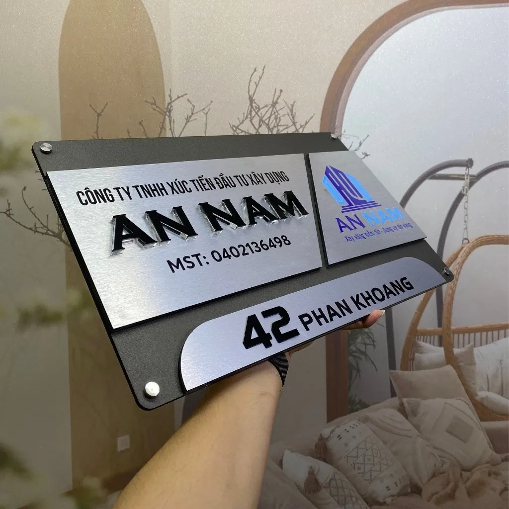 Bảng hiệu công ty inox xám khói bạc xước 3 mảnh ghép chữ nổi đen logo màu góc nghiêng trái thấy rõ cấu trúc module