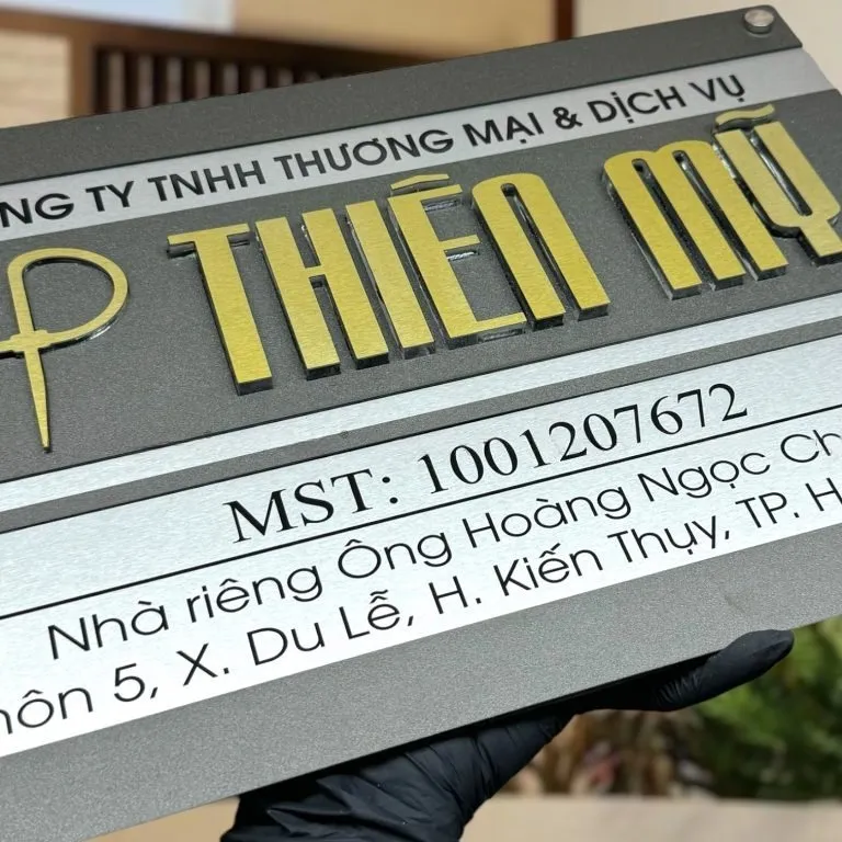 Bảng hiệu công ty inox xám khói bạc xước chữ nổi 3D vàng nhìn góc nghiêng phải thấy rõ 2 lớp inox