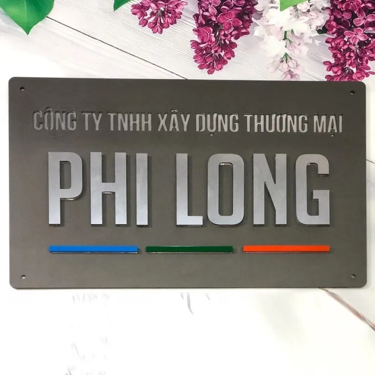 Bảng hiệu công ty inox sơn xám mờ chữ nổi trắng xước 3D – thanh màu trang trí tùy chỉnh Mặt trước bảng hiệu công ty inox sơn tĩnh điện xám mờ, chữ nổi 3D inox trắng xước, thanh màu xanh dương – xanh lá – cam trang trí, cạnh vuông