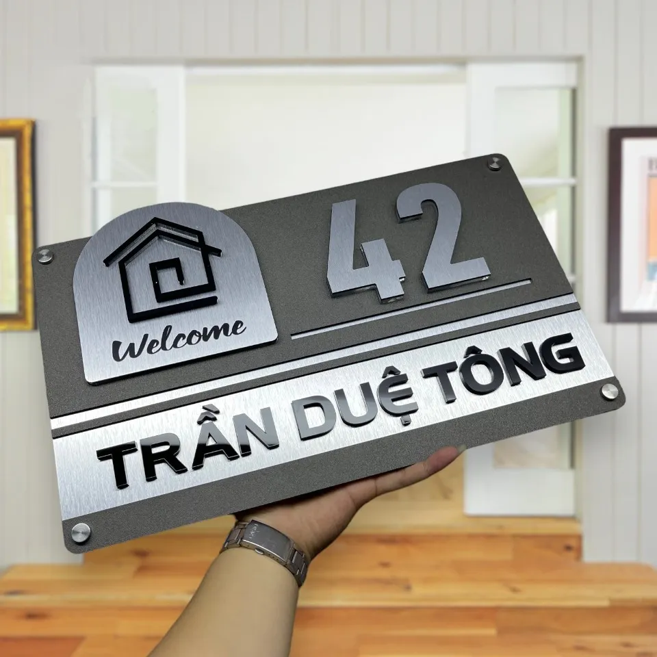 Bảng số nhà inox xước bạc nhìn góc nghiêng cho thấy cạnh viền vàng và chiều dày bảng