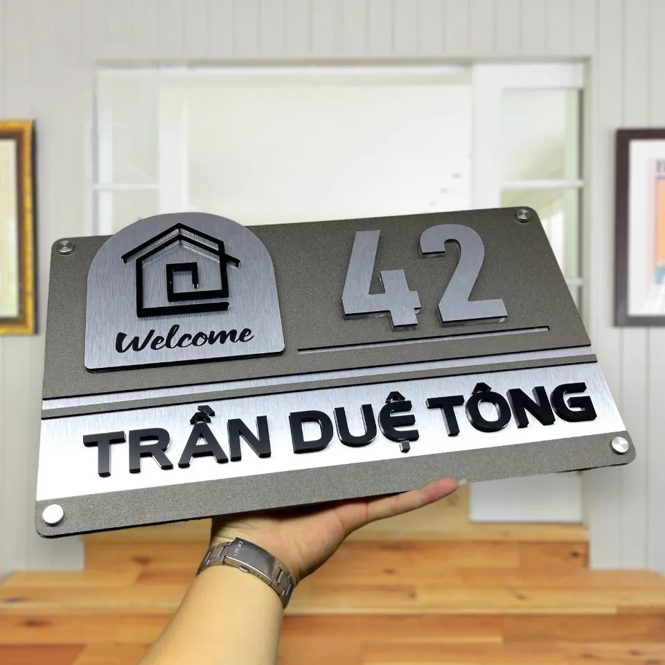 Toàn cảnh bảng số nhà inox 304 xước bạc chữ nổi 3D mẫu Welcome đặt trên nền gỗ sáng
