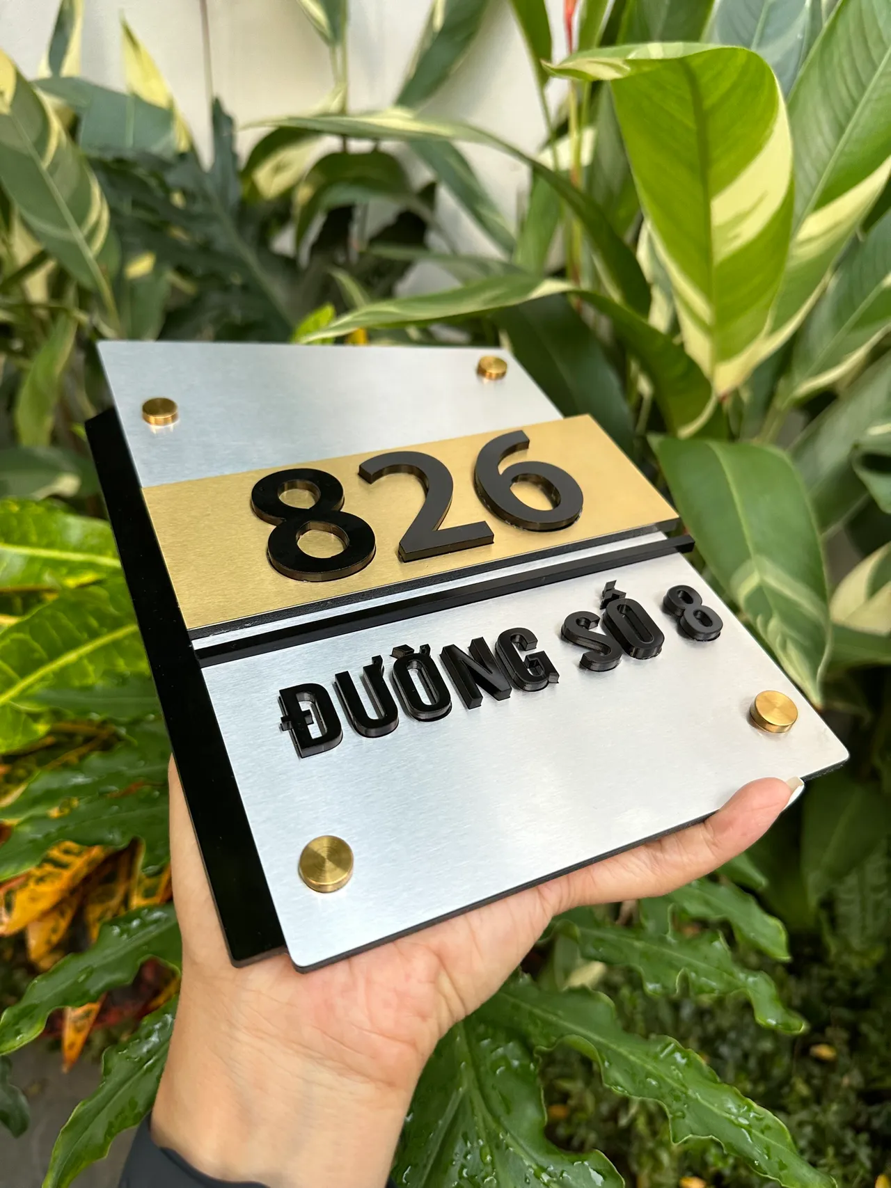 Bảng số nhà inox bạc vàng chữ đen nổi 3D nhìn từ góc nghiêng phải – thấy lớp đen bóng phía sau và dải vàng nổi