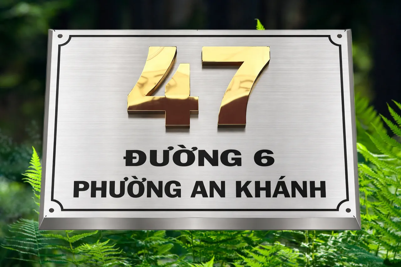 Bảng số nhà inox xước bạc số vàng gương nổi 3D viền vát chéo bốn mặt phong cách cổ điển sang trọng – chụp góc cao nền cây xanh tối nổi bật