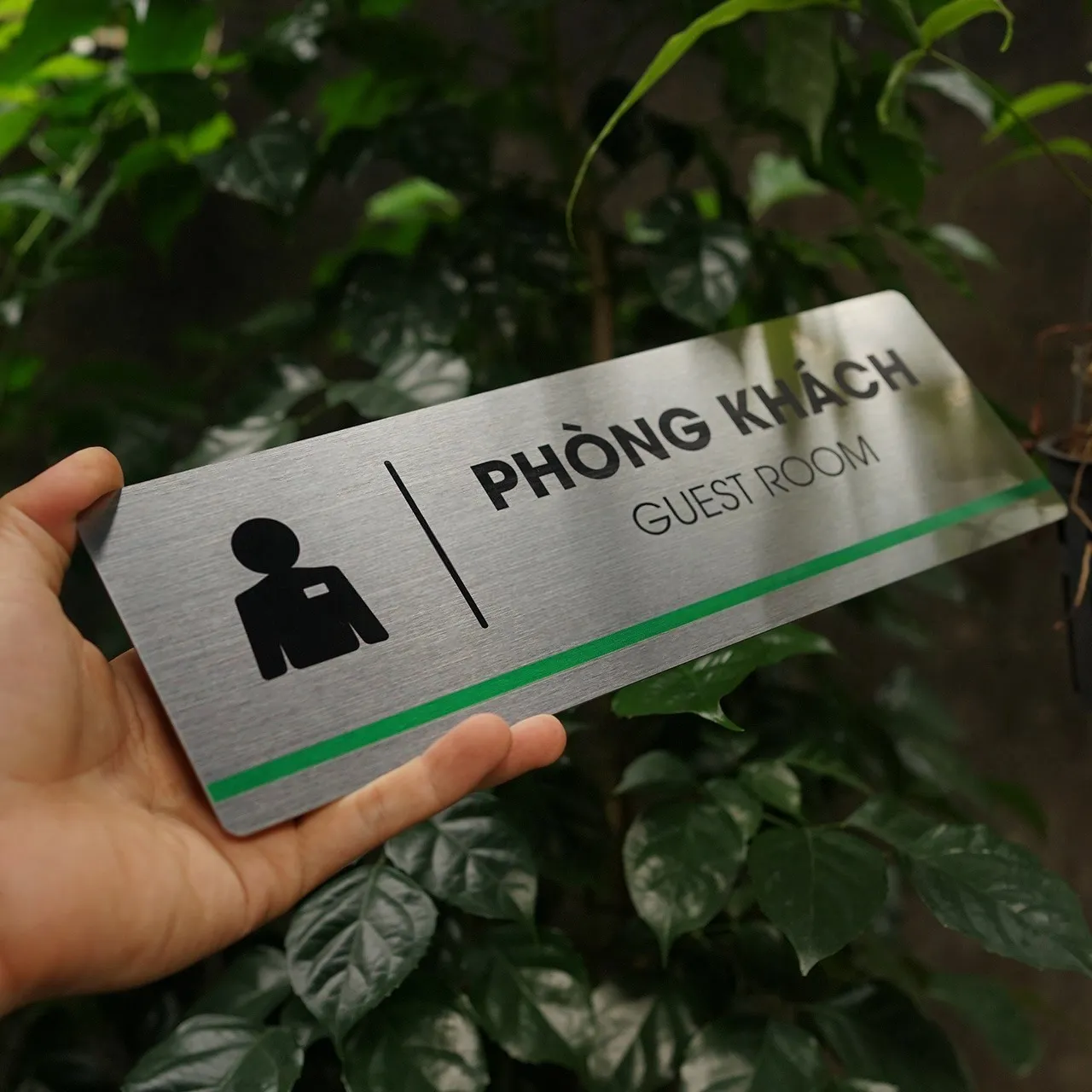 Bảng tên phòng khách inox 304 cầm tay góc nghiêng trái – hiệu ứng ánh kim bề mặt Bảng tên phòng khách inox 304 phay xước cầm tay góc nghiêng trái ánh kim bề mặt nền lá tối