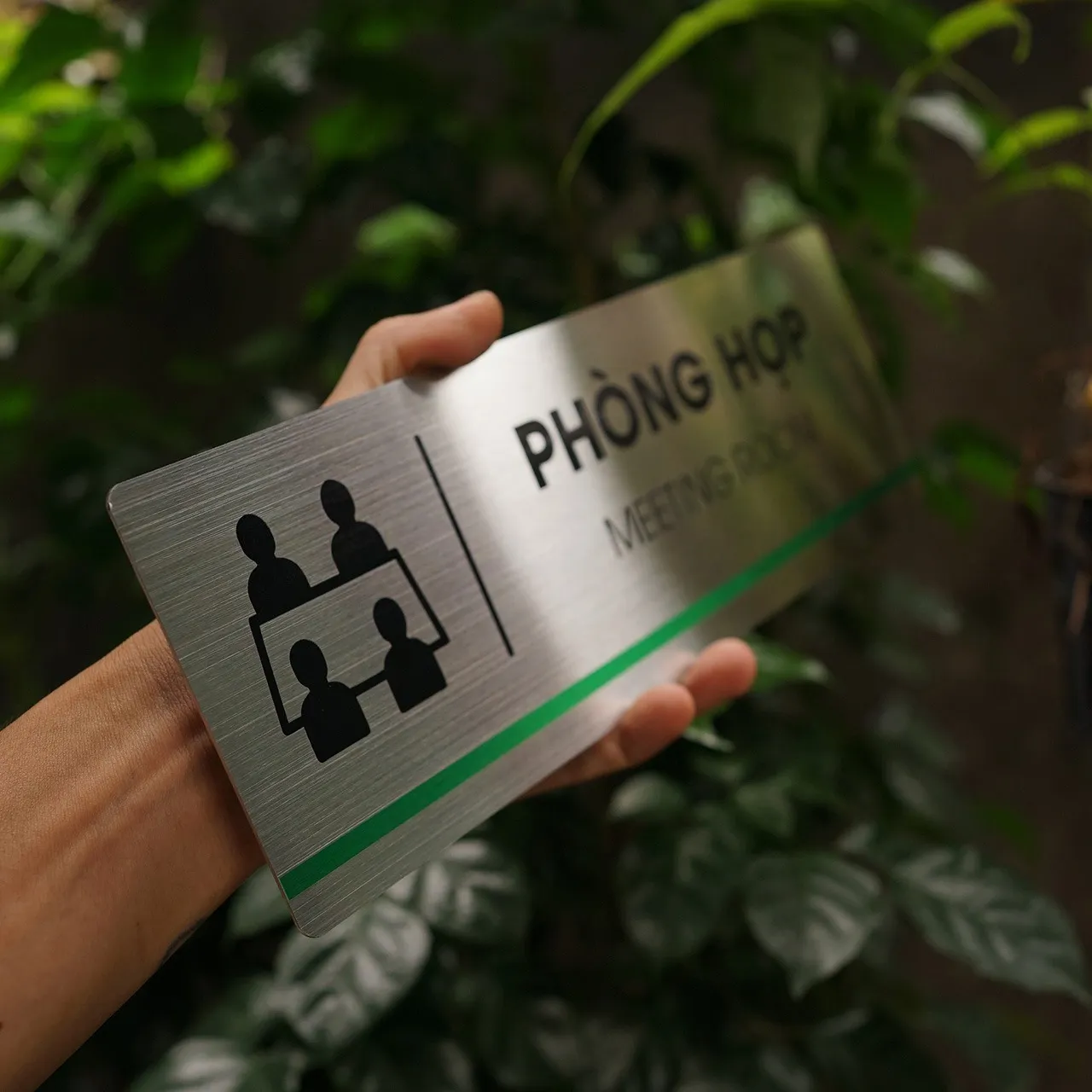 Cận cảnh pictogram bàn họp bốn người ăn mòn hóa học sắc nét trên nền inox 304 phay xước