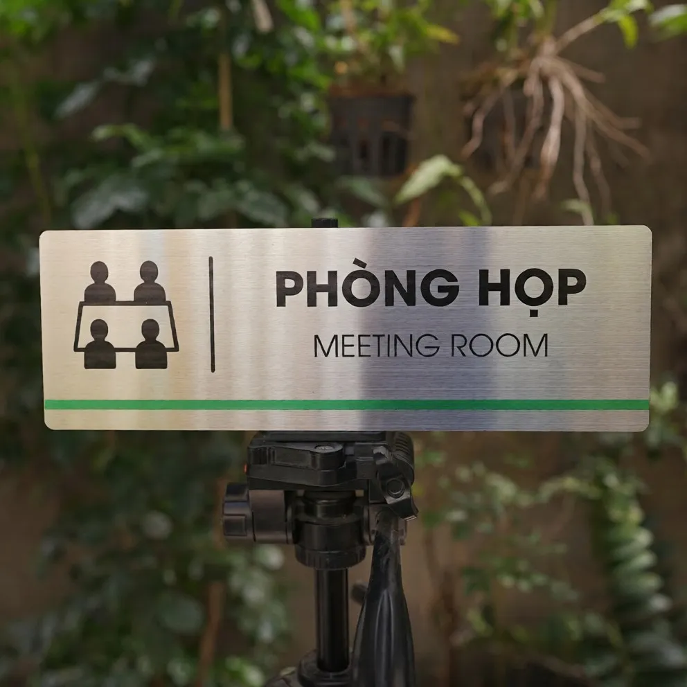 Bảng tên phòng họp inox 304 trên giá đỡ mặt trước thẳng thấy rõ pictogram bàn họp và sọc xanh lá