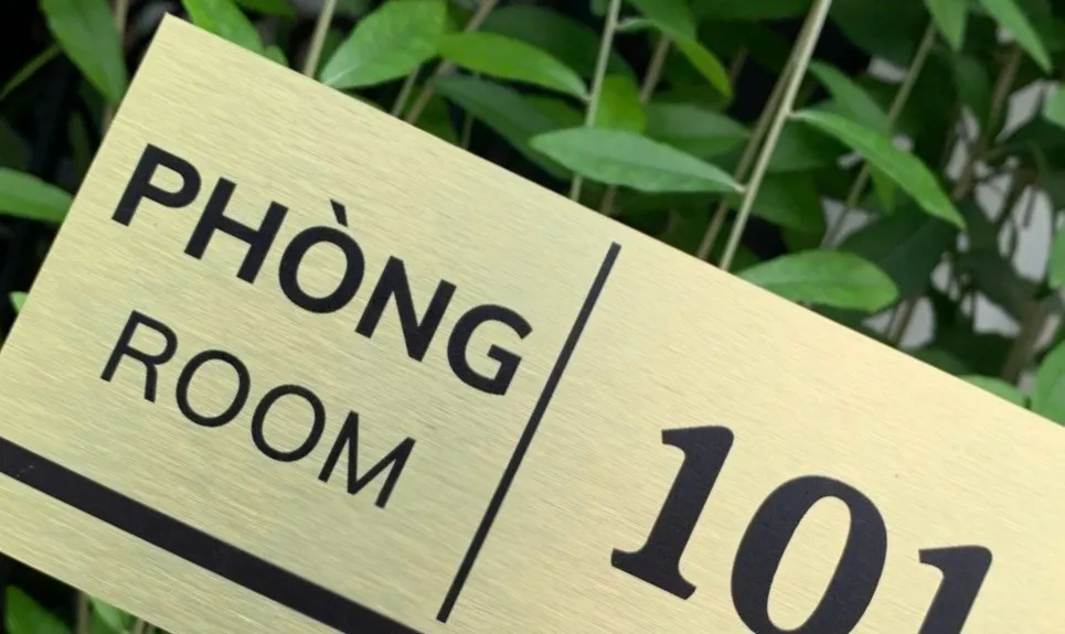 Cận cảnh bố cục chữ PHÒNG ROOM và đường kẻ dọc trên bảng số phòng inox