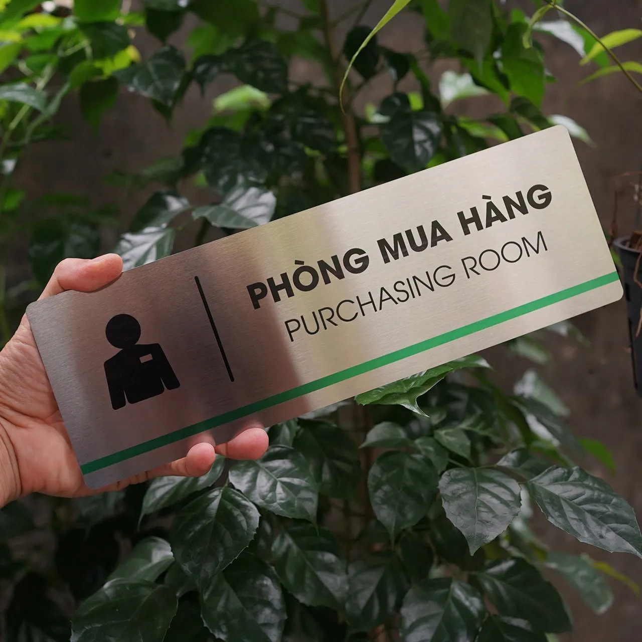 Bảng tên phòng mua hàng inox 304 phay xước cầm tay mặt trước thẳng dưới ánh sáng tự nhiên